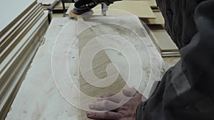 A worker in the furniture industry grinds wood products with a grinder.