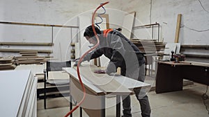 A worker in the furniture industry grinds wood products with a grinder.