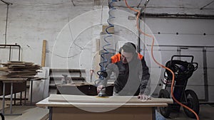 A worker in the furniture industry grinds wood products with a grinder.