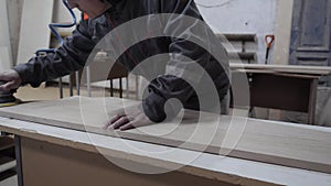 A worker in the furniture industry grinds wood products with a grinder.