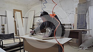 A worker in the furniture industry grinds wood products with a grinder.