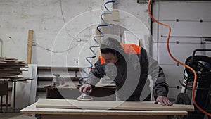 A worker in the furniture industry grinds wood products with a grinder.
