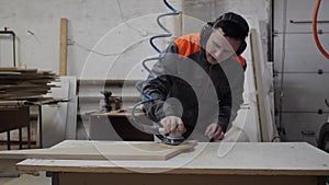 A worker in the furniture industry grinds wood products with a grinder.