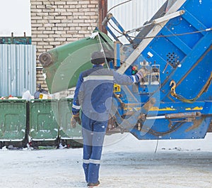 Worker at garbage collection, loading barrels in a garbage can