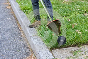 Worker in gasoline mower in hand man mows the grass with string trimmer