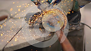 Worker in gloves cutting a metal pipe angle grinder, close up