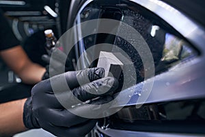 Worker in gloves waxing the car wheel tire closeup. Automobile care