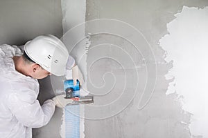 A worker glues the seams with a special mesh tape on a concrete wall using a spatula, there is a place for your inscription