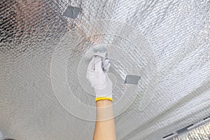 A worker glues staples from a stapler to a vapor barrier film