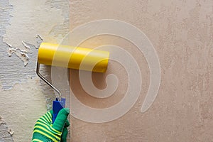 A worker glues wallpaper with a roller on an unprepared wall. The concept of repairing a house or apartment