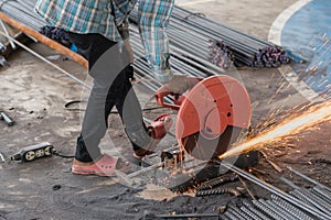 Worker with grinder machine cutting metal reinforcement rebar rods