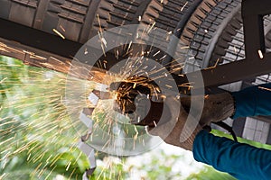 Worker grinding and cutting metalsheet of roof