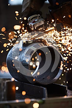 Worker grinding on a metal tube with yellow sparks flying