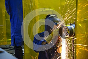 The worker grinding the steel pipe after welding