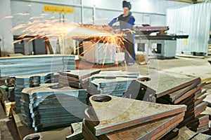 Worker grinding weld seam with grinder machine and sparks