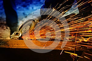Worker grinding/welding metal and sparks spreadi photo