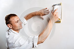 Worker grinding white wall with sandpaper. Copy space.