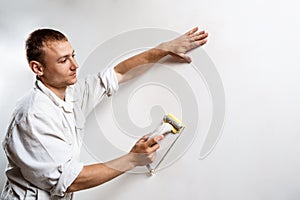 Worker grinding white wall with sandpaper. Copy space.