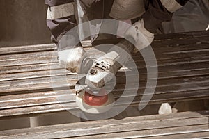 A worker grinds a rusty metal pipe