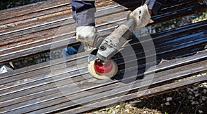 A worker grinds a rusty metal pipe