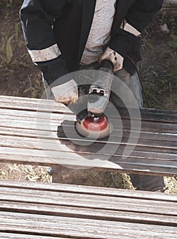 A worker grinds a rusty metal pipe