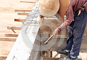 Worker hammering a nail to install wooden formwork for pour concrete beam