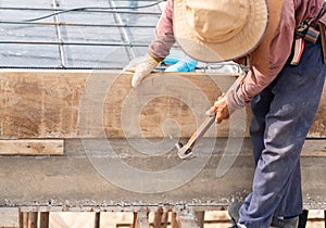 Worker hammering a nail to the wooden formwork