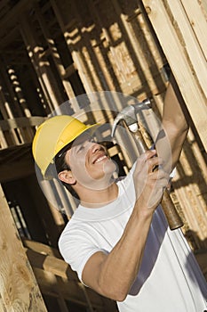 Worker Hammering Nail On Wooden Wall