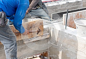 Worker hammering nails on wooden formwork for concrete beam
