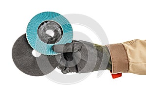 Worker hand in black protective glove and brown uniform holding abrasive flap disc and cutting abrasive disc for angle grinder