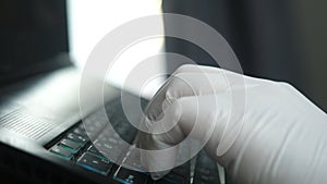 Worker hand with glove working with a computer typing on a laptop