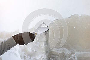 Worker hand holding trowel to peel off wall paint, Old house wall painter.