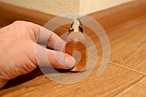 Worker with a hand installs the corner of the baseboard