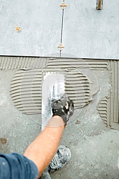 Worker hand plastering, adding adhesive with comb trowel