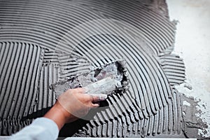 Worker hand plastering a wall, adding adhesive with comb trowel photo