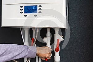 Worker hand remote or installing double-circuit gas boiler for winter home heating and water heating. Energy saving and