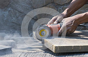 Worker hand using grinder cutting stone tile floor for paving pavement