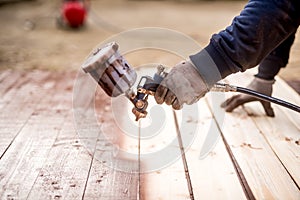 Worker hand using spray gun and painting wood