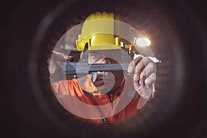 Worker handles metal at lathe Turner measures the dimensions of the metal workpiece with a caliper in uniform with safety. Work on