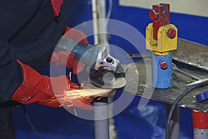 worker hands grinding metal plate with a grinder, preparing for welding