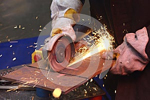 worker hands grinding metal plate with a grinder, preparing for welding