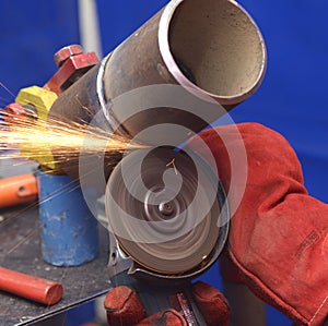 worker hands grinding metal tube with a grinder, preparing for welding