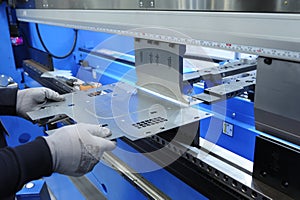 Worker hands holding the metal sheet working with the CNC hydraulic press brake machine