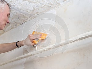 Worker hands holding a spatula with white putty. Repair and renovation at home. New interior design.