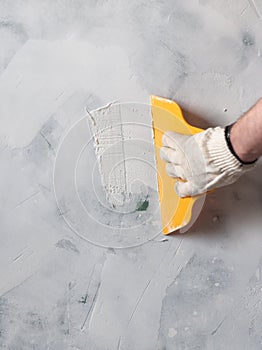 Worker hands holding a spatula with white putty. Repair and renovation at home. New interior design.