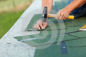 Worker hands installing bitumen roof shingles photo