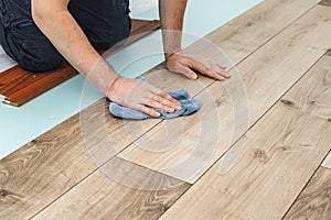 Worker hands installing timber laminate floor. Easy and quick installation of the flooring - connecting laminate locks - DIY