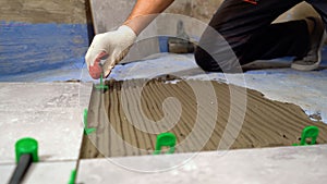 Worker hands placing spacers between ceramic floor tiles. Installing a large ceramic tile. Installation of fasteners