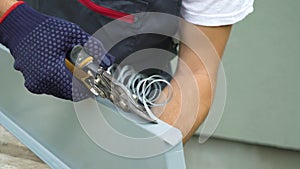 Worker hands in protective gloves preparing PVC window sill cutting metal with scissors closeup