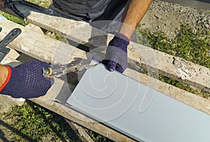 Worker hands in protective gloves preparing PVC window sill cutting metal with scissors closeup